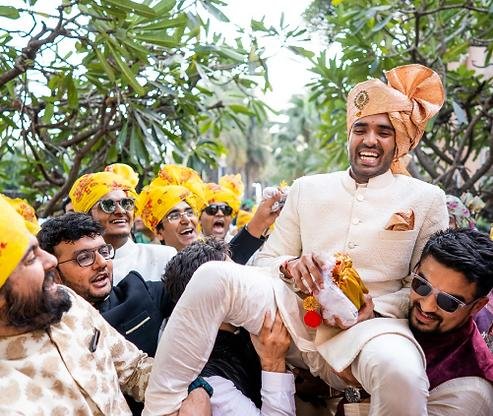 Indian groom laughing with family members at a wedding